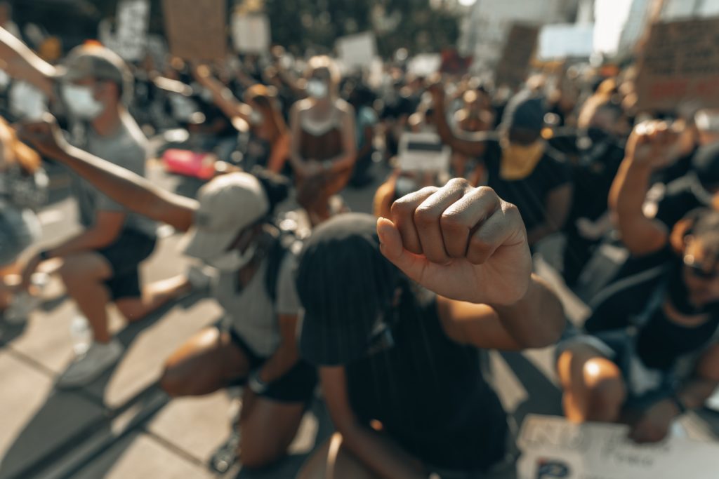 Image of demonstrators kneeling with their fists in the air